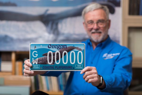 Bruce Mate holding a gray whale license plate